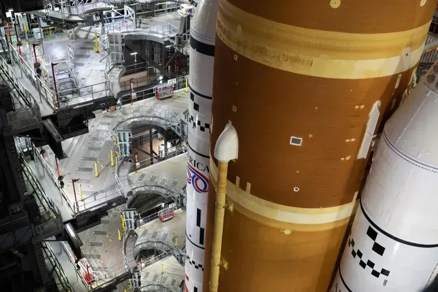 O foguete Artemis II Space Launch System (SLS) da NASA e a espaçonave Orion, fixados à plataforma de lançamento móvel, são vistos dentro do prédio de montagem de veículos em 16 de janeiro no Centro Espacial Kennedy da NASA, na Flórida • Joel Kowsky/NASA