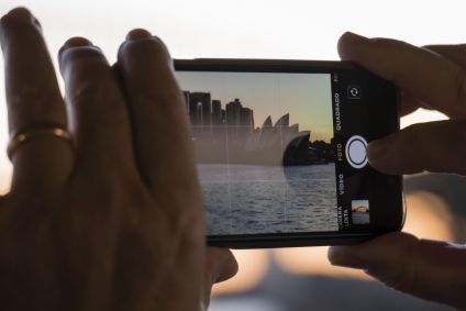 pessoa-fotografando-paisagem-urbana-com-smartphone-ao-por-do-sol-opera-house-e-arranha-ceus-ao-fundo-foto-mobile