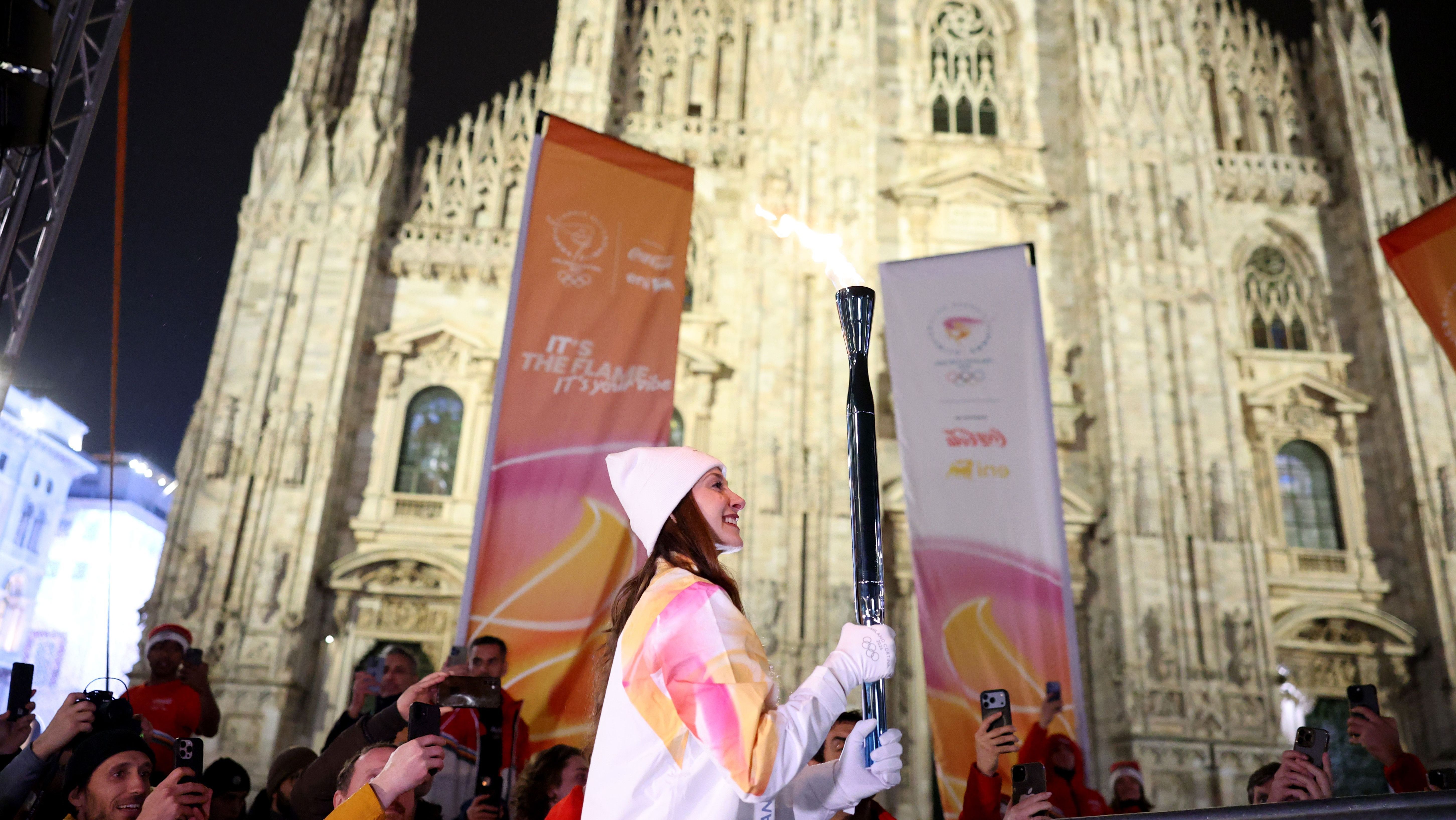 A bailarina italiana Nicoletta Manni segura a tocha olímpica em frente ao Duomo di Milano, na véspera da cerimônia de abertura dos Jogos Olímpicos de Inverno