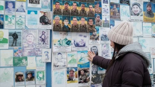 Oksana Borkun observa o retrato de seu marido exposto em um muro que homenageia os soldados ucranianos mortos em combate em Kiev.