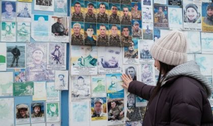 Oksana Borkun observa o retrato de seu marido exposto em um muro que homenageia os soldados ucranianos mortos em combate em Kiev.