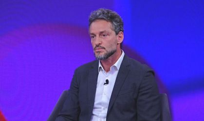 André Lavor, presidente da Binatural, sentado em um fundo azulado, com um terno cinza.