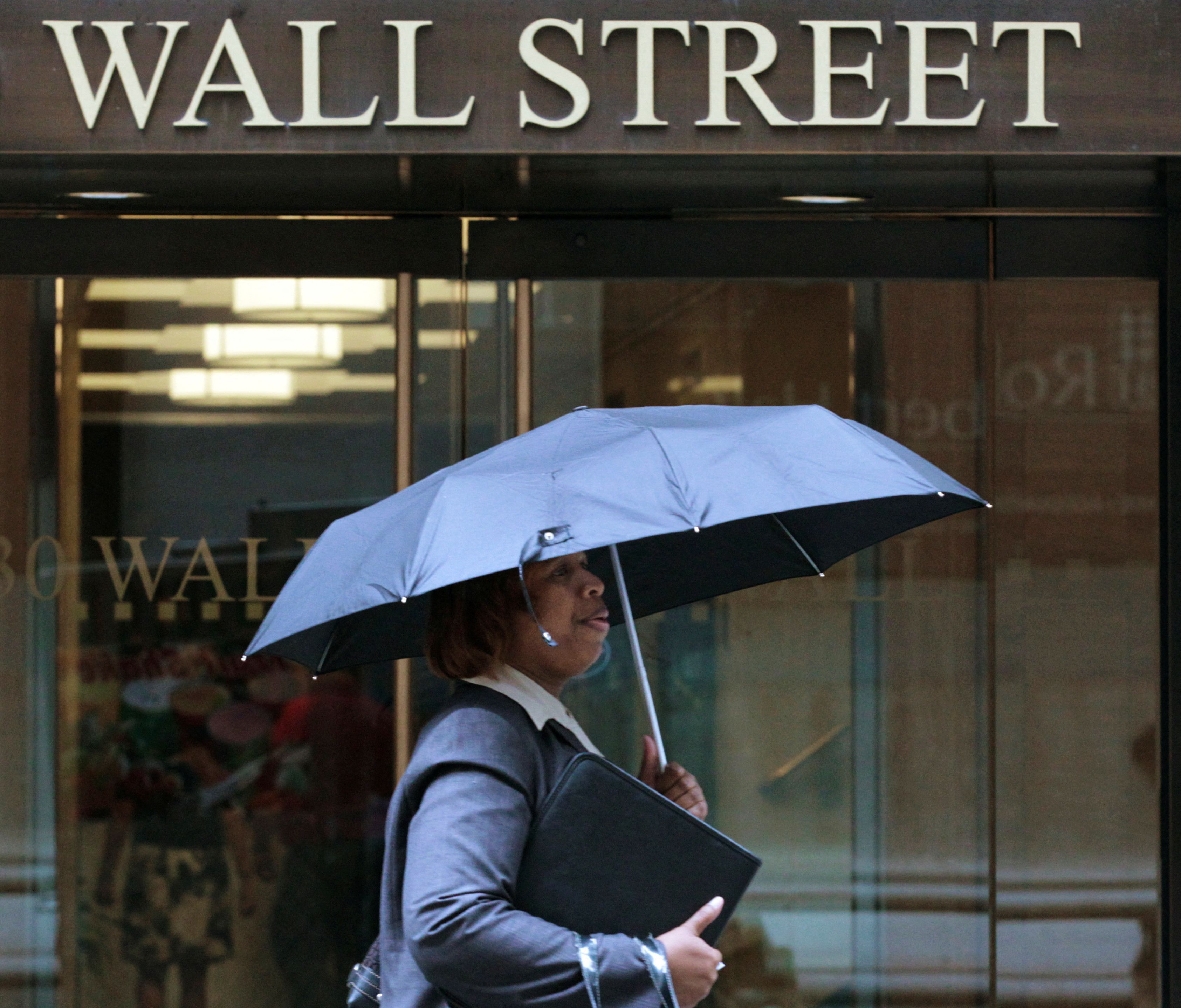 Mulher caminha em meio à chuva em Wall Street, Nova York