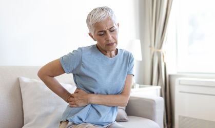 Unhealthy mature woman holding belly, feeling discomfort, health problem concept, unhappy older female sitting on bed, suffering from stomachache, food poisoning, gastritis, abdominal pain, climax