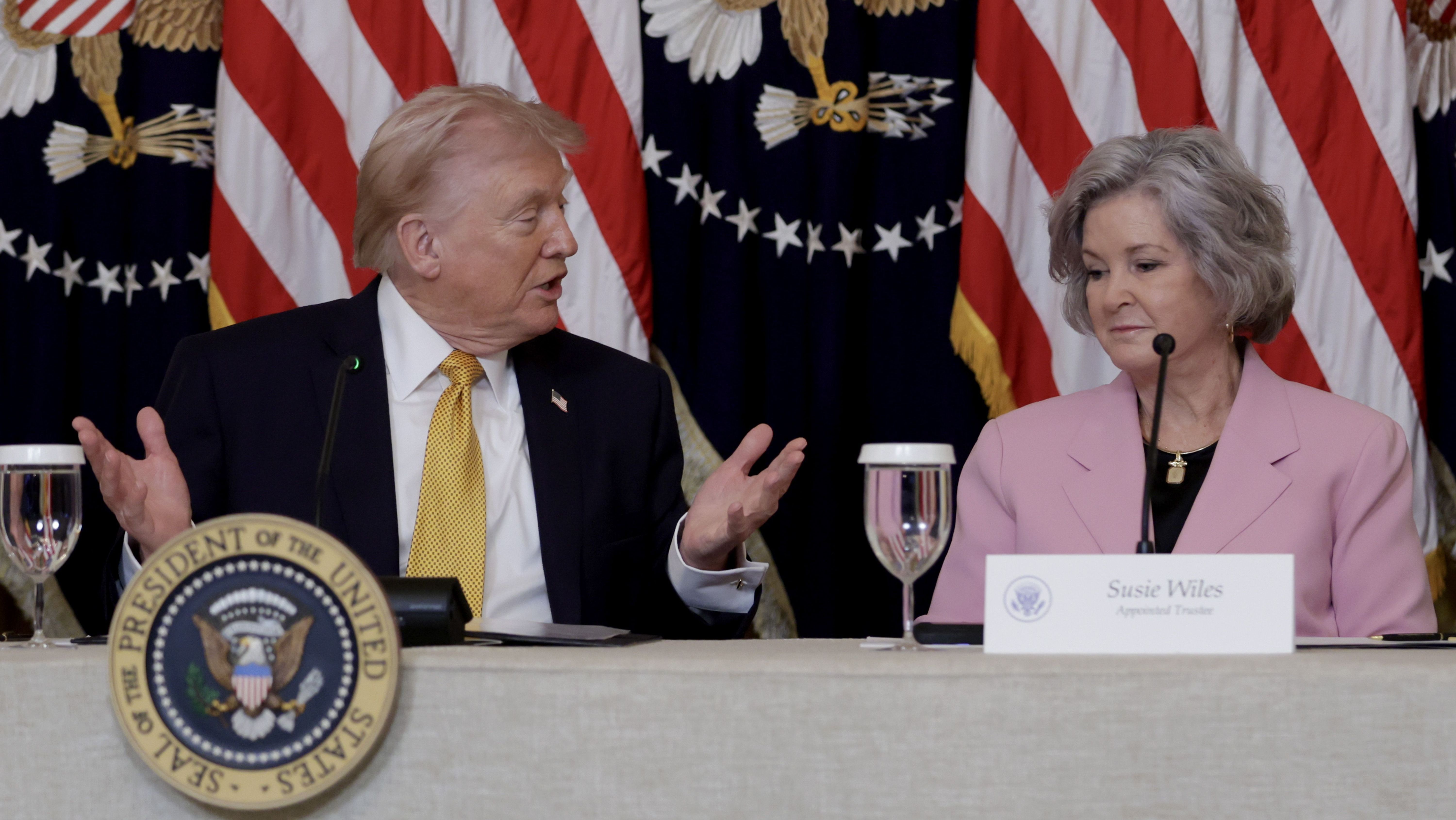 O presidente dos EUA, Donald Trump, senta-se com a chefe de gabinete da Casa Branca, Susie Wiles, enquanto discursa durante um almoço com os membros do Conselho do Trump Kennedy Center no Salão Leste da Casa Branca, em 16 de março de 2026, em Washington, DC.
