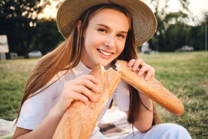 adolescente-com-chapéu-de-palha-segurando-uma-baguete