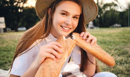 adolescente-com-chapéu-de-palha-segurando-uma-baguete