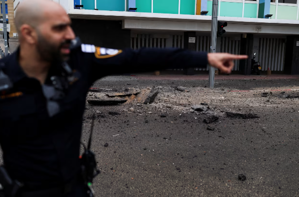policial israelense gesticula no local dos danos causados ​​pelo lançamento de mísseis iranianos contra Israel em Tel Aviv,