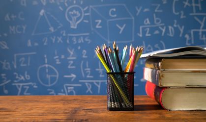 Back to school supplies. Books and blackboard on wooden background