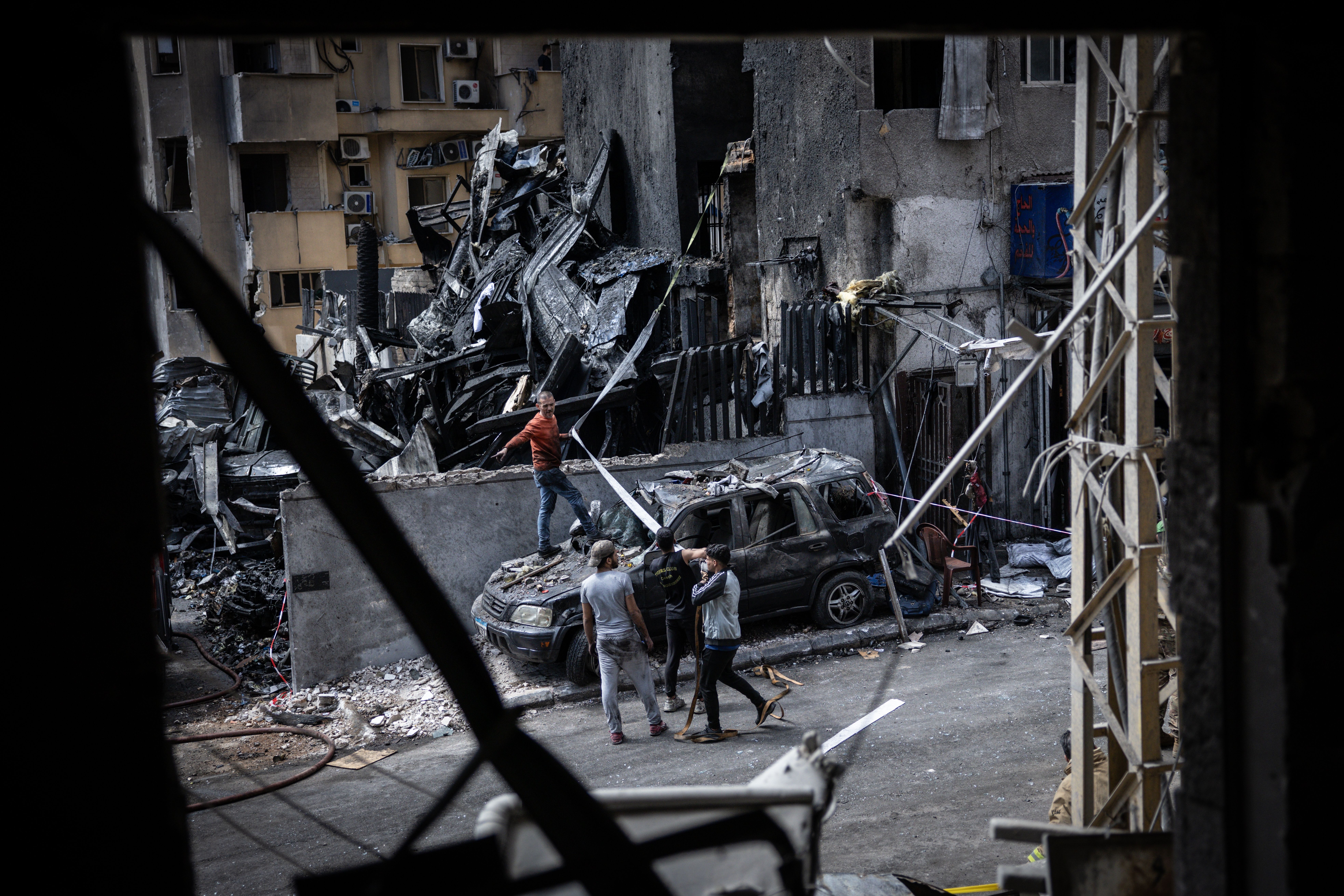Pessoas tentam remover um veículo destruído em um ataque aéreo israelense em Beirute, no Líbano