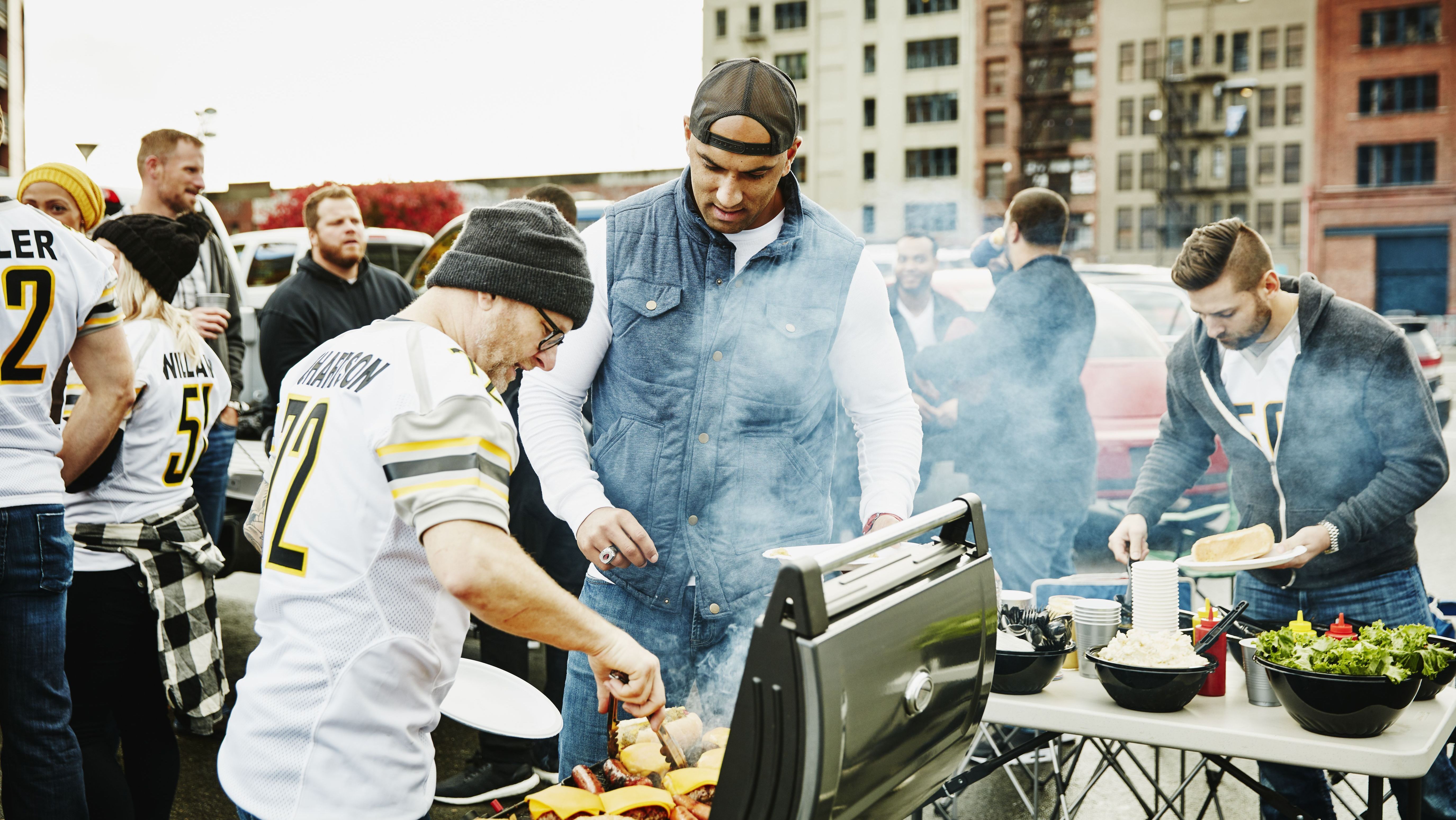 Men cooking at barbecue during tailgating party