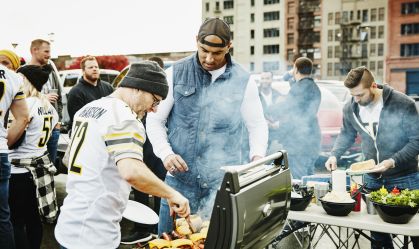 Men cooking at barbecue during tailgating party