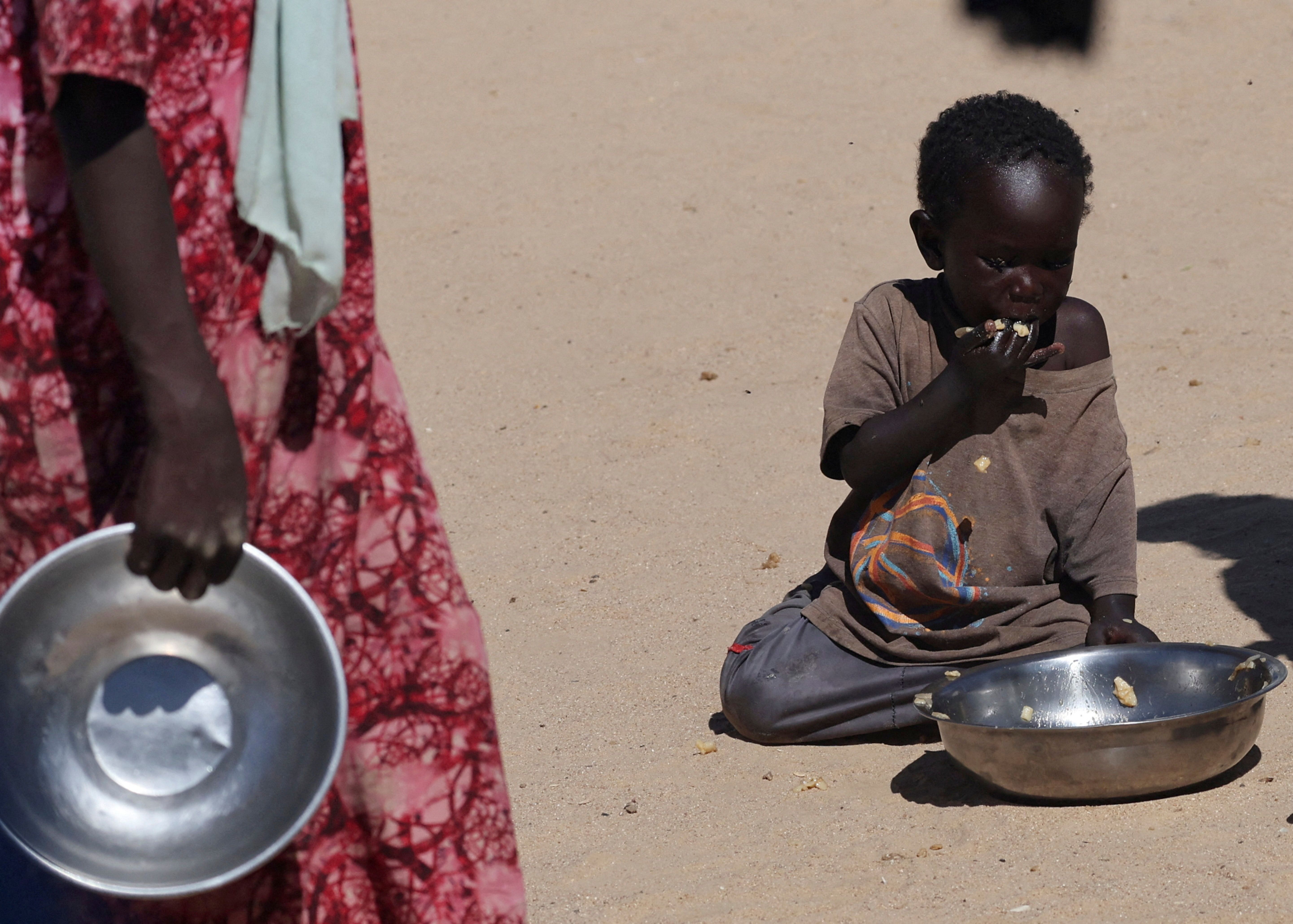 Criança sudanesa órfã refugiada de al-Fashir se alimenta em campo de trânsito de Tine, no leste do Chade