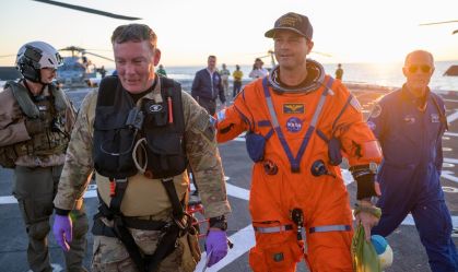 O astronauta Reid Wiseman, comandante da Artemis II, é auxiliado a sair do convés de voo após chegar a bordo do USS John P. Murtha