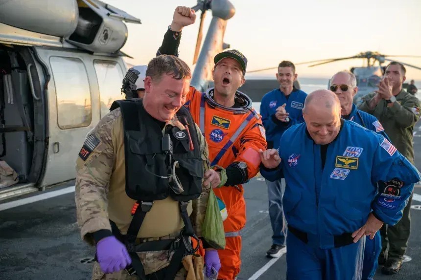 O astronauta da NASA Reid Wiseman, comandante da Artemis II, recebe ajuda para sair do convés de voo após chegar a bordo do USS John P. Murtha na sexta-feira • Bill Ingalls/NASA