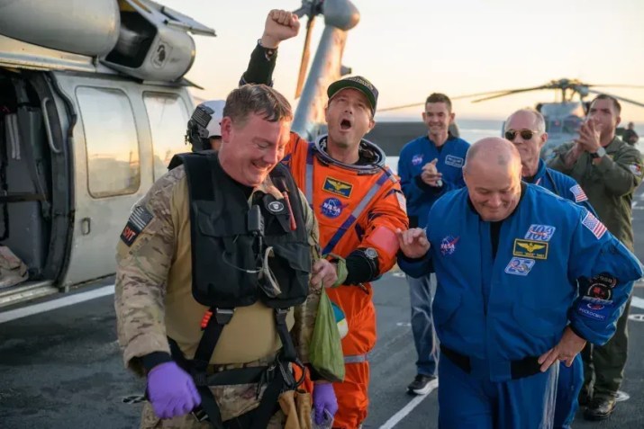 O astronauta da NASA Reid Wiseman, comandante da Artemis II, recebe ajuda para sair do convés de voo após chegar a bordo do USS John P. Murtha na sexta-feira • Bill Ingalls/NASA