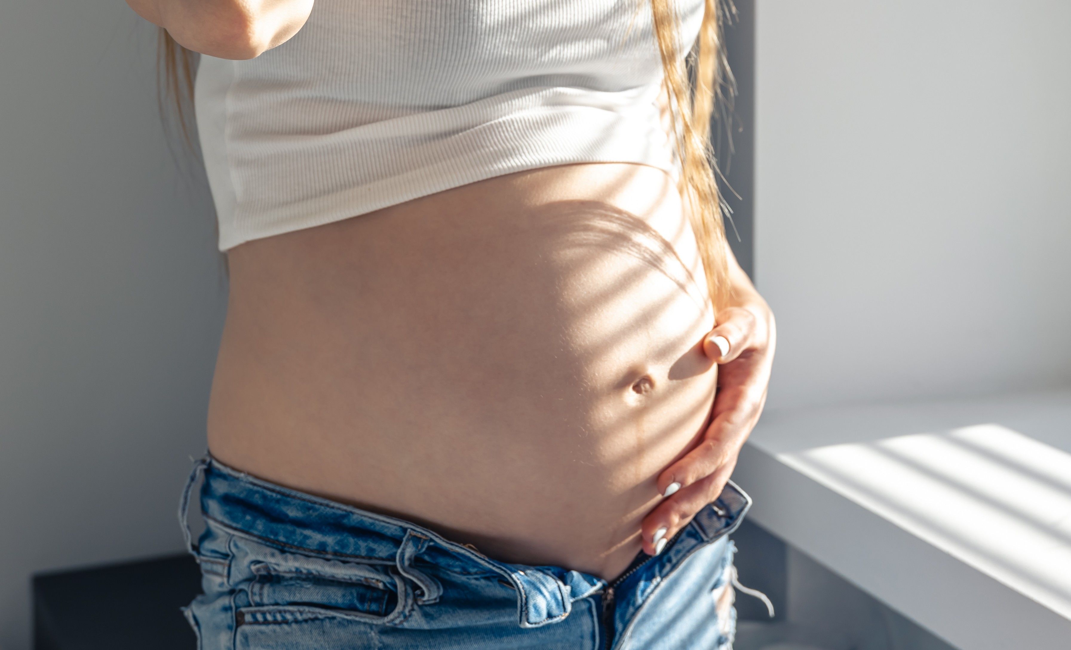 Attractive young pregnant woman on a sunny morning at the window.