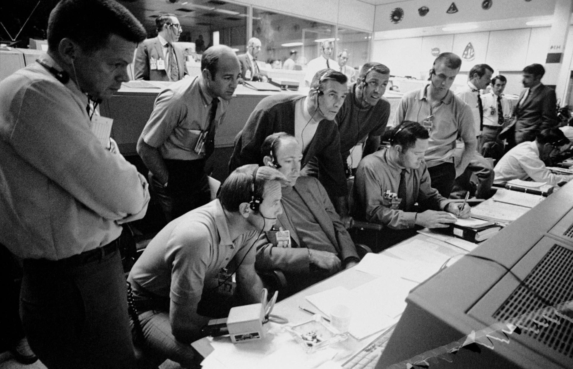 Um grupo de seis astronautas e dois controladores de voo monitoram a atividade do console na Sala de Controle de Operações da Missão (MOCR) do Centro de Controle da Missão (MCC) durante a problemática missão de pouso lunar Apollo 13 • Nasa