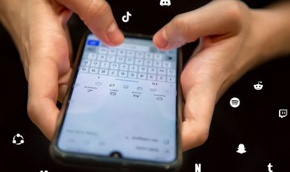 photo of hands holding a cellular phone with black background screen on with social media icons