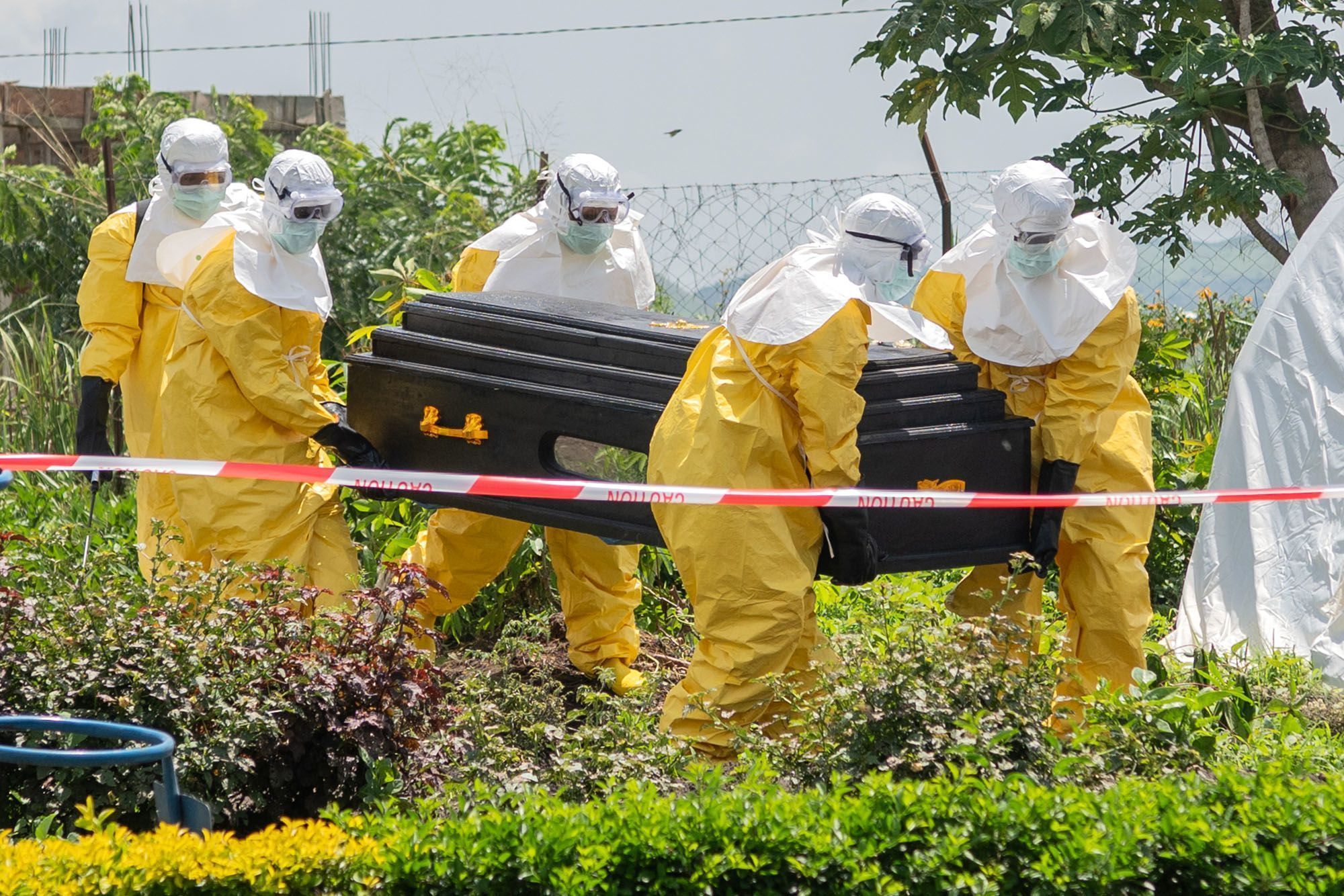 Em 20 de maio, funcionários da Cruz Vermelha carregam o caixão de uma pessoa que morreu de Ebola em um centro de saúde em Rwampara, República Democrática do Congo