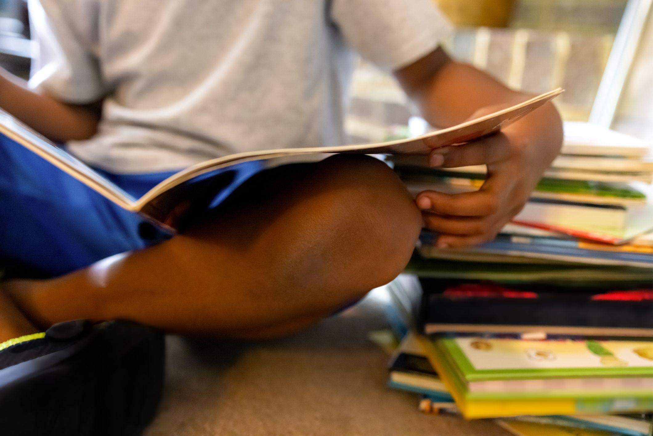 young black boy reading beside a large stack of books