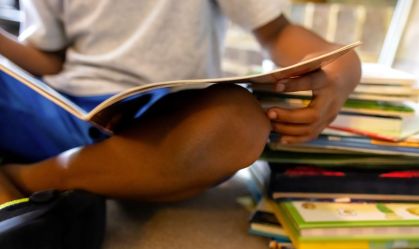 young black boy reading beside a large stack of books