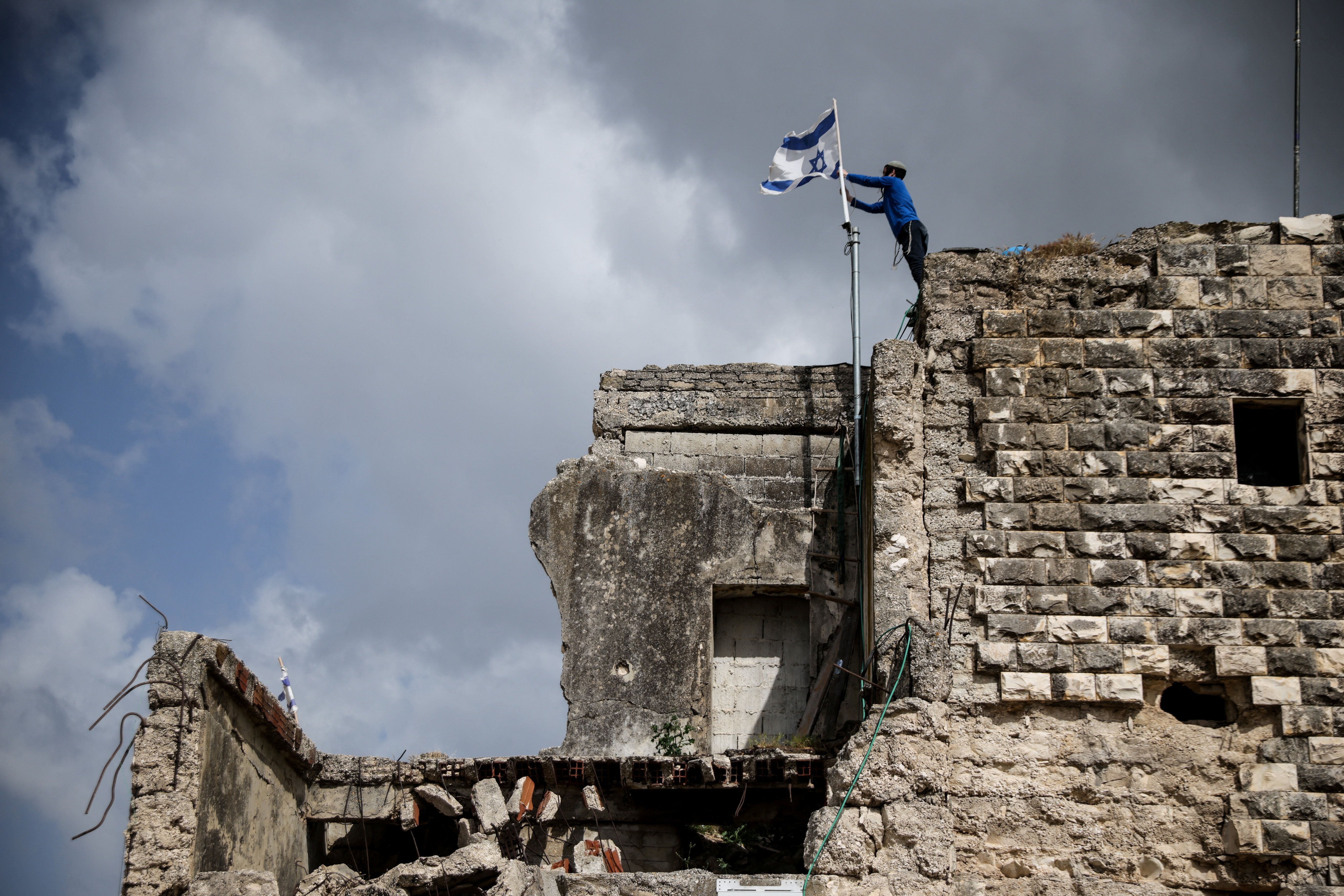 Colono israelense instala bandeira de Israel, no dia do restabelecimento do assentamento de Sa-Nur, na Cisjordânia ocupada por Israel
