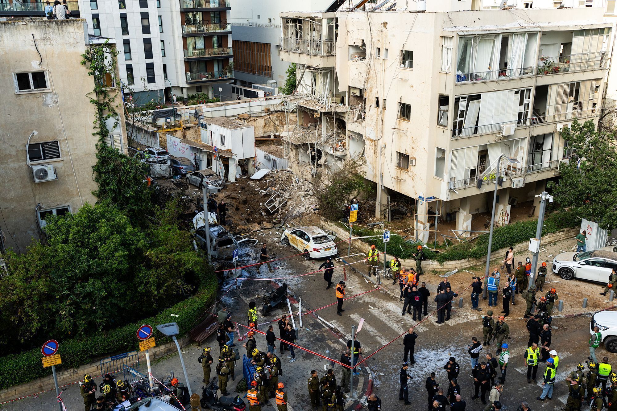 Equipes de resgate se reúnem perto da cratera deixada por um míssil iraniano em 24 de março de 2026 em Tel Aviv, Israel. • Ilia Yefimovich/AFP/Getty Images via CNN Newsource