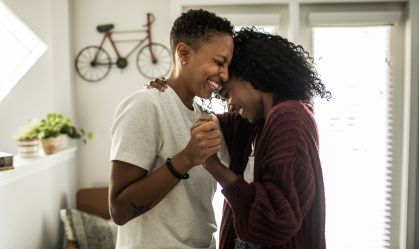 Lesbian couple dancing in living room