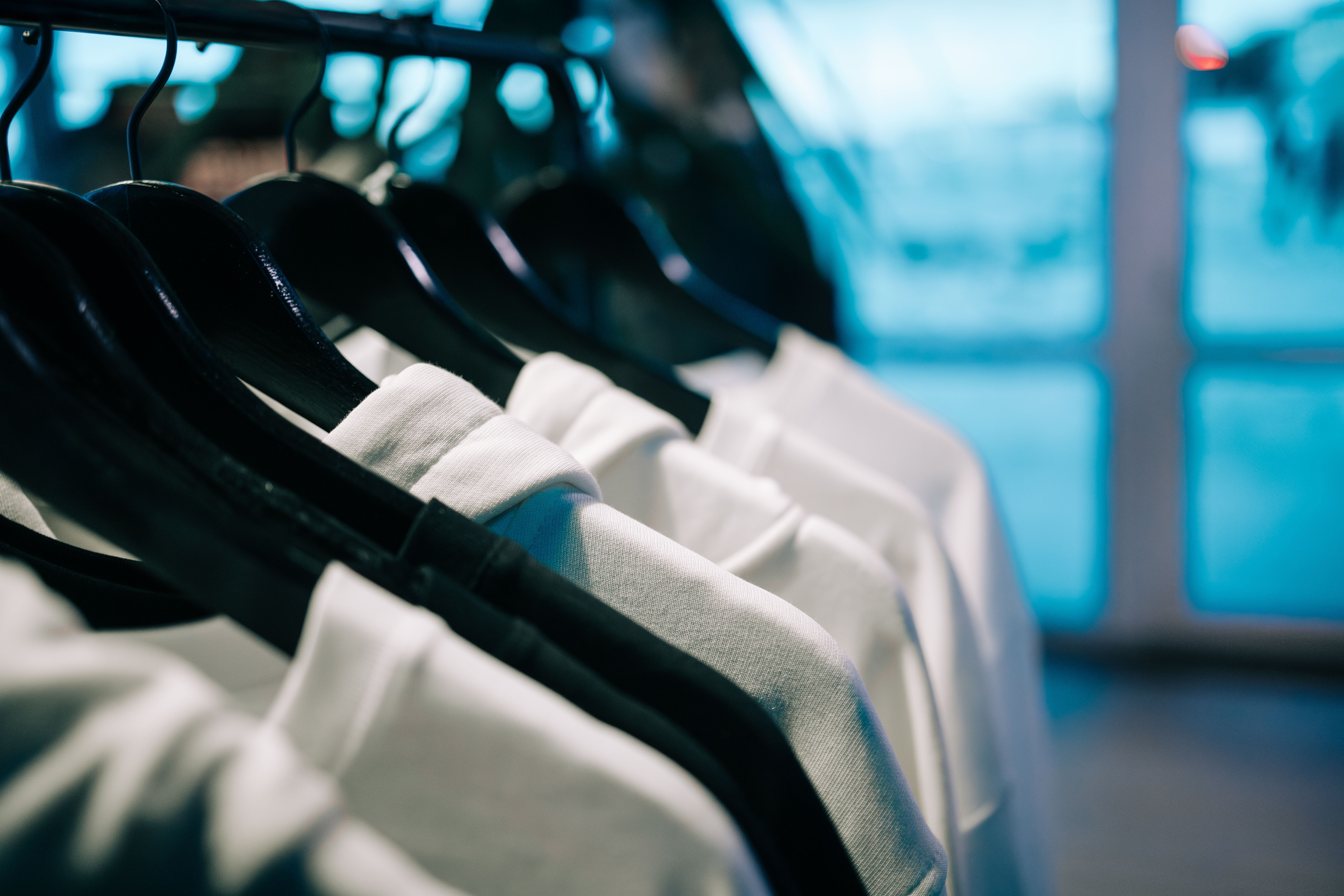 White hoodies hanging on hangers in clothing store
