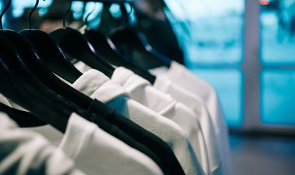 White hoodies hanging on hangers in clothing store