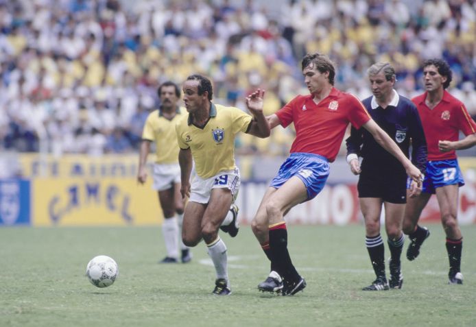 Referee Chris Bambridge looks on as Elzo #19, Defensive Midfielder for the Brazil national football team and Julio Salinas #19, Forward for the Spain national football team challenge for the football during their 1986 FIFA World Cup Group D match on 1st June 1986 at the Estadio Jalisco, Guadalajara, Mexico. The Brazil won the match 1 - 0. (Photo by David Cannon/Allsport/Getty Images) • Getty Images