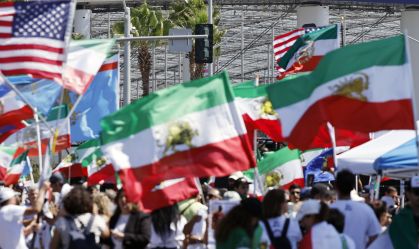 Manifestantes protestam contra a República Islâmica do Irã, exibindo bandeiras iranianas pré-revolucionárias e outras bandeiras, em frente ao Estádio de Los Angeles, nesta segunda-feira (15)