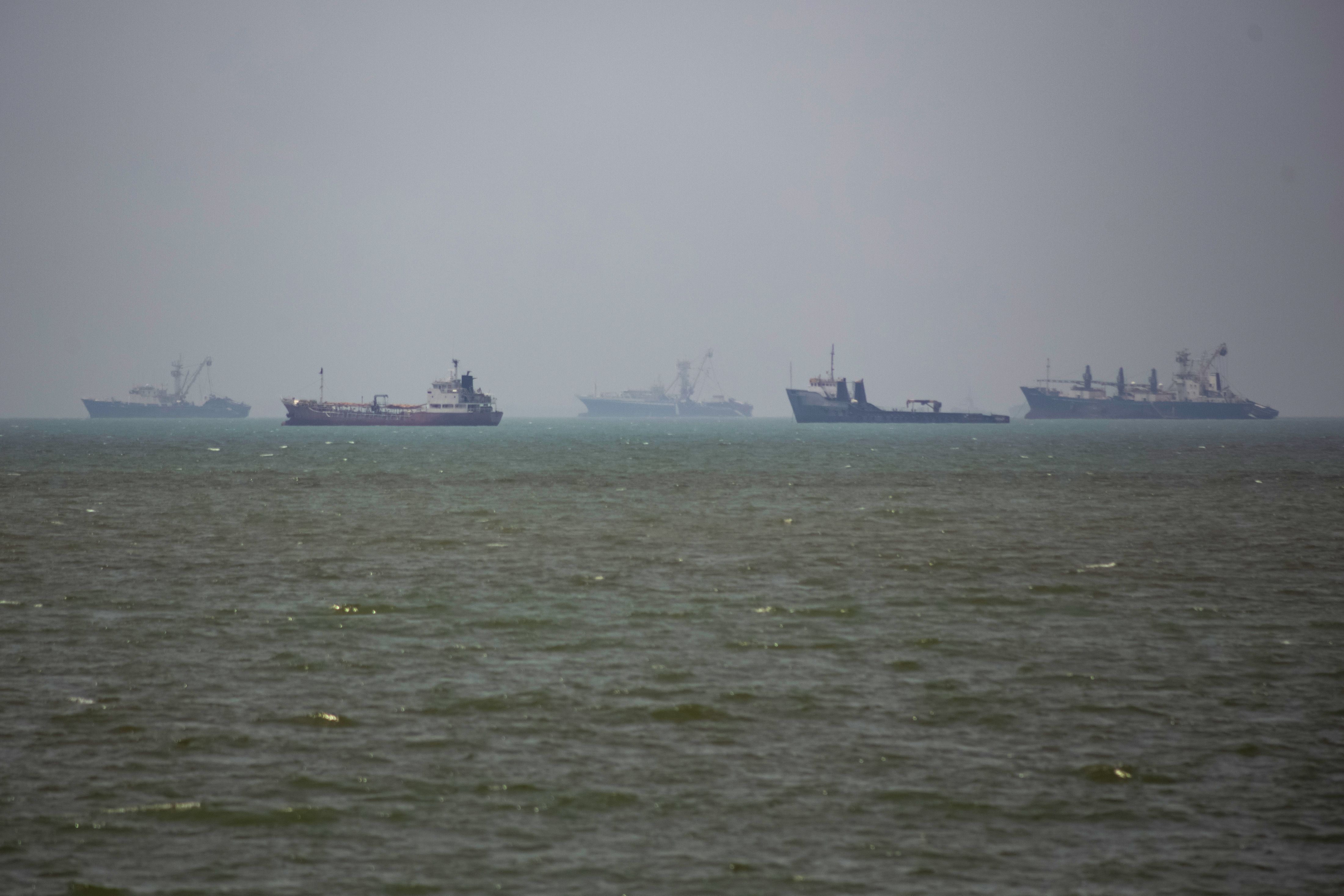 Grandes embarcações comerciais e um pequeno barco navegam pelas águas da cidade portuária de Bandar Abbas, no sul do Irã, no Estreito de Ormuz em 21 de junho de 2026