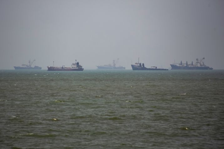 Grandes embarcações comerciais e um pequeno barco navegam pelas águas da cidade portuária de Bandar Abbas, no sul do Irã, no Estreito de Ormuz em 21 de junho de 2026 • Hassan Ghaedi/Anadolu via Getty Images