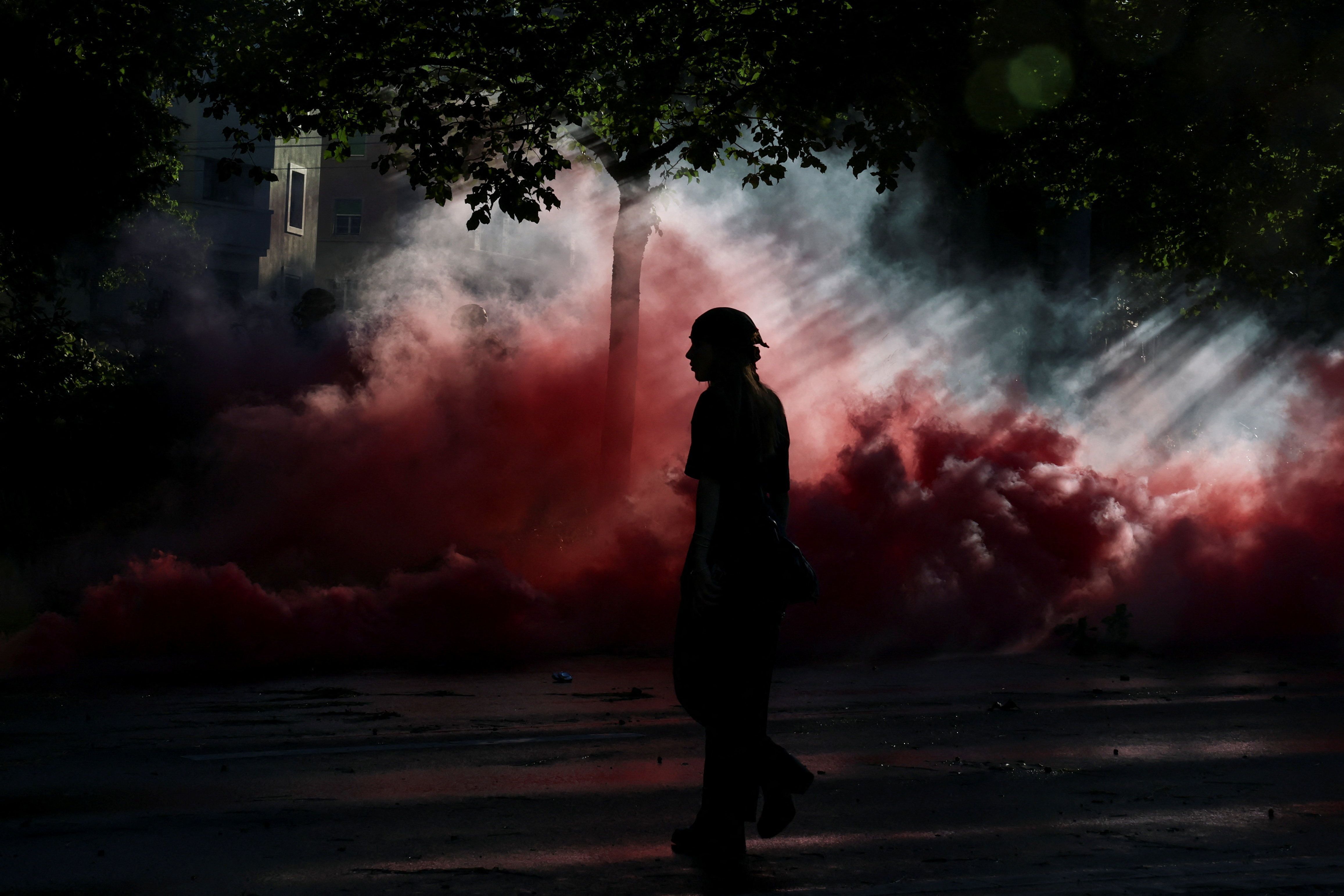 Pessoa caminha em meio a nuvens de fumaça durante protesto em Genebra contra a próxima cúpula do G7