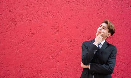Young Latino man in a suit and tie considering his options, man deep in thought, looking up