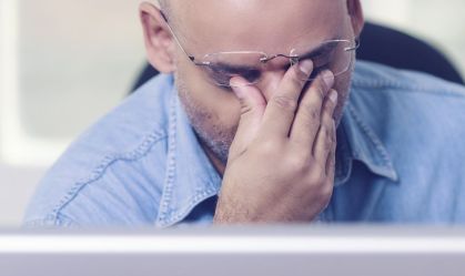 Middle-aged black man in front of the computer tired of working or stressed about bad news