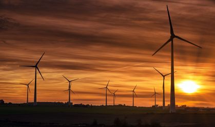 Silhouette of windmills on a field during sunset