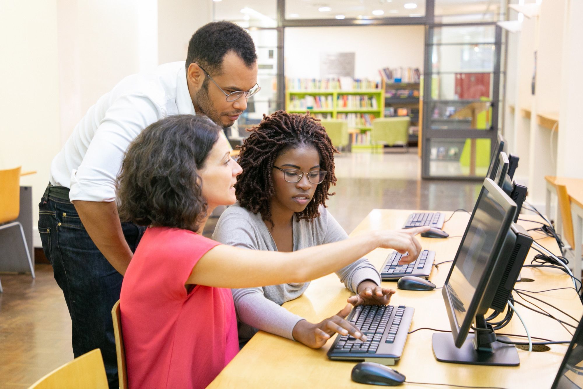 professor-orientando-alunas-em-aula-com-computador