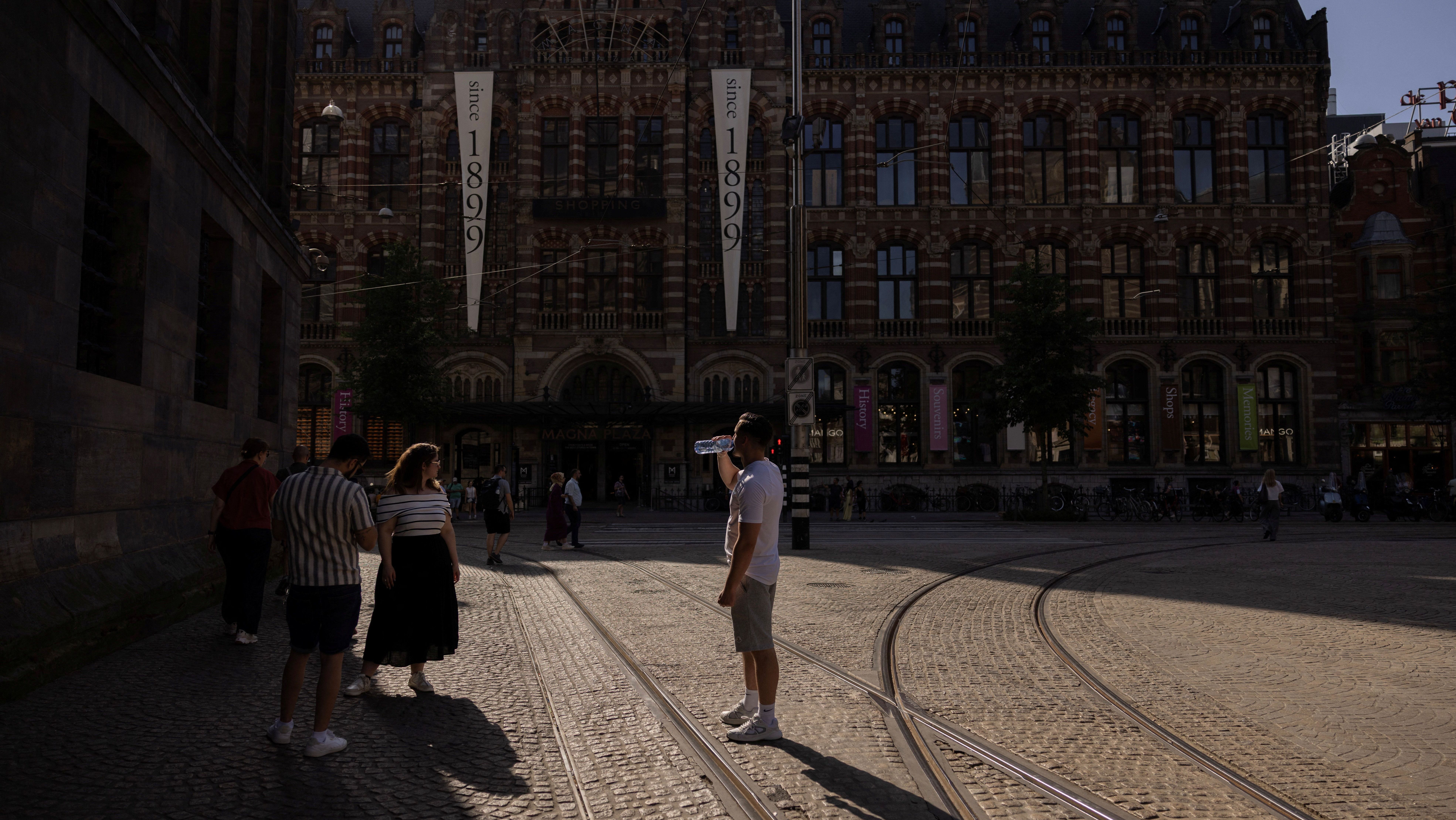 Homem bebe água durante um dia excepcionalmente quente na Praça Dam, em Amsterdã