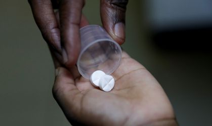 Enfermeira entrega medicamento ARV (antirretroviral), usado para impedir a replicação do HIV, a uma criança em orfanato no distrito de Karen, em Nairóbi, Quênia