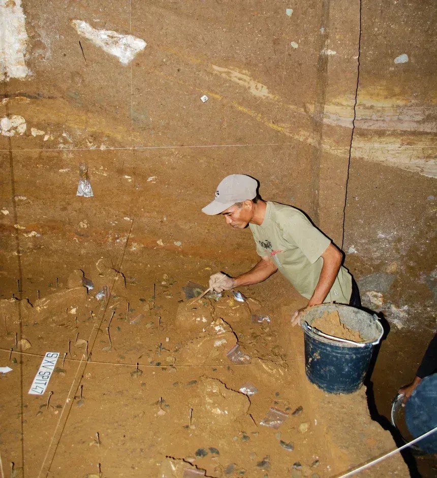 Benyamin Tarus, membro da equipe de escavação, trabalha em depósitos de Homo floresiensis no sítio arqueológico de Liang Bua • Equipe Liang Bua