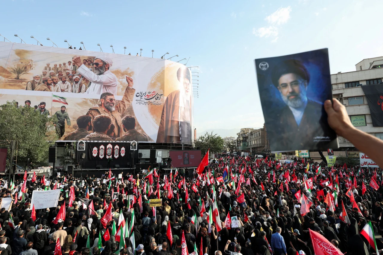Um participante do funeral segura uma foto do Líder Supremo Mojtaba Khamenei durante o cortejo fúnebre do falecido Aiatolá Ali Khamenei em Teerã, Irã, na segunda-feira