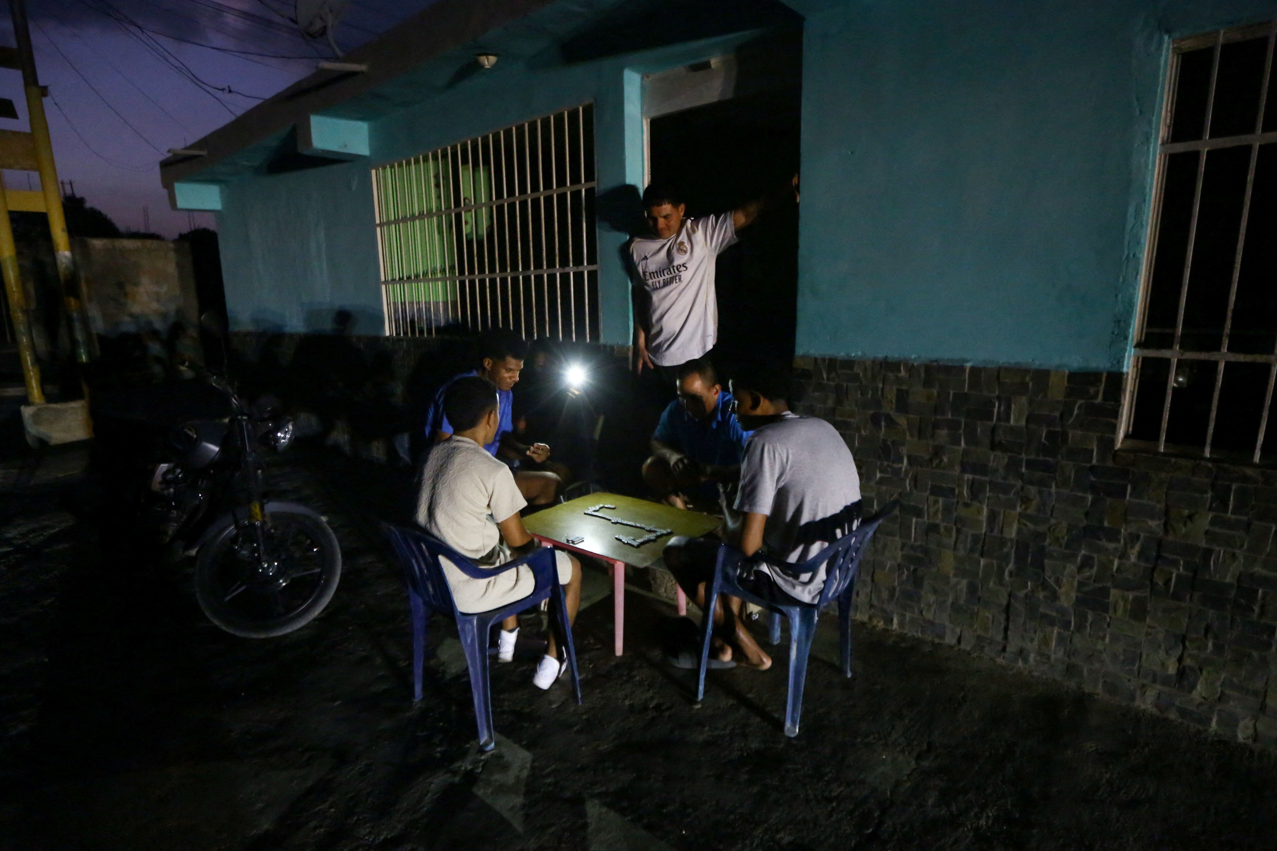 Pessoas jogam dominó com luz de celular durante apagão em Valência, na Venezuela
