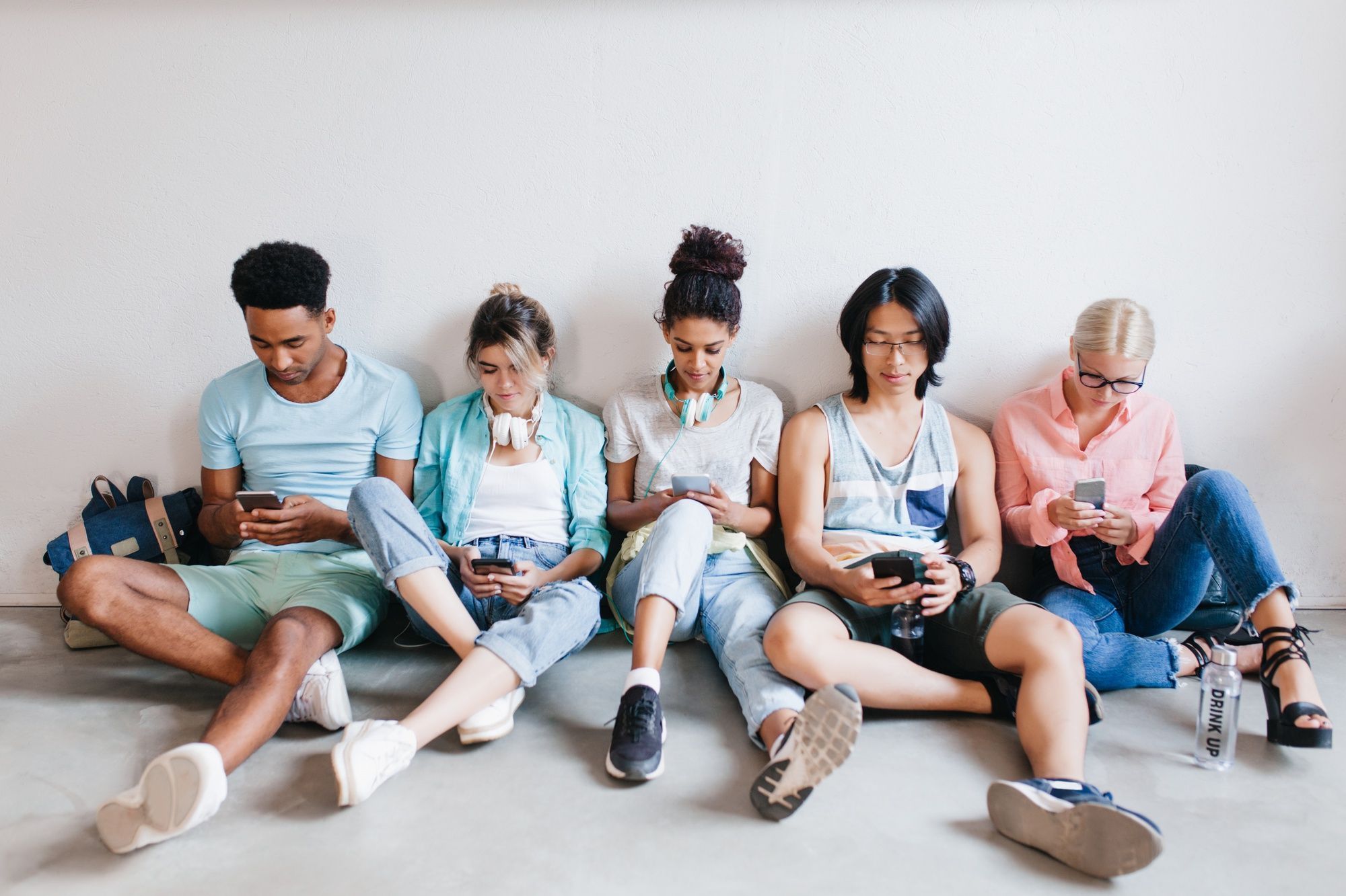 jovens-sentados-lado-a-lado-usando-celulares-sem-conversar-entre-si