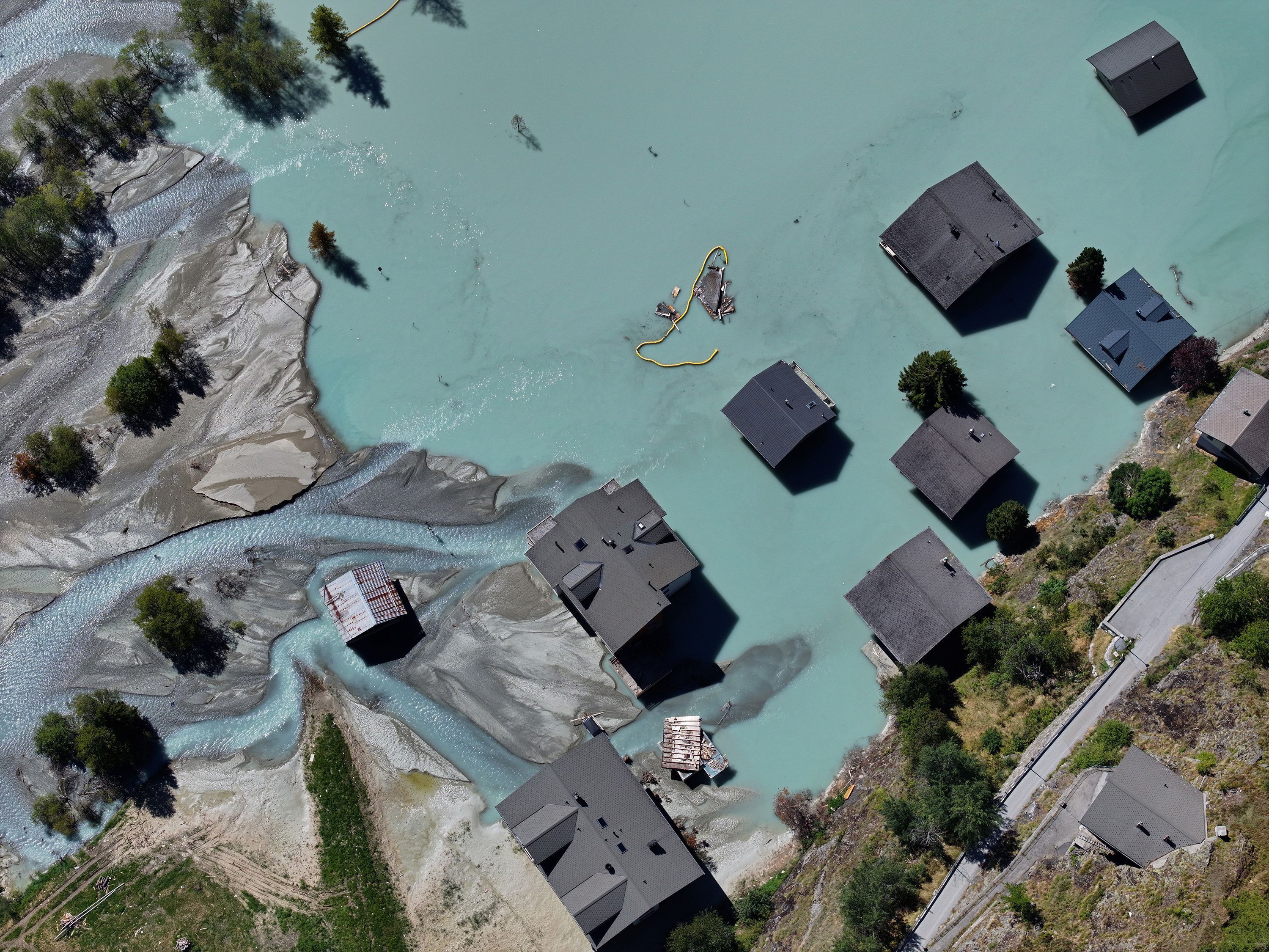 Casas submersas em água que chegou em 24 de agosto de 2025 a Blatten, na Suíça. Em 28 de maio, milhões de metros cúbicos de rocha desabaram da montanha Kleiner Nesthorn sobre a geleira Birch, lançando rochas, gelo e lama no vale. • Sean Gallup/Getty Images via CNN Newsource