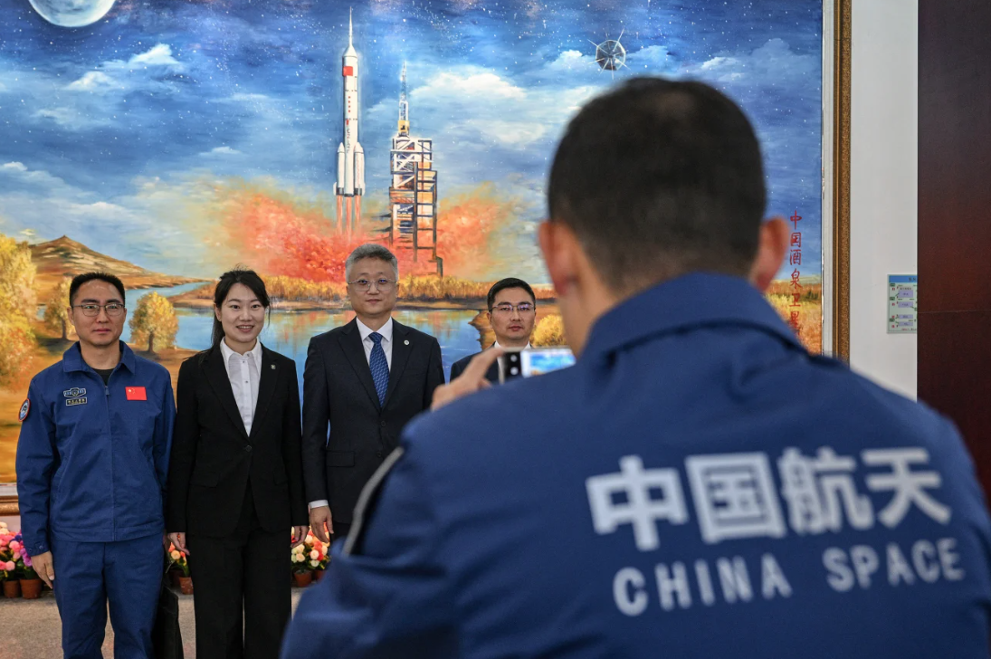 Zhang Jingbo (terceiro da esquerda para a direita), porta-voz do Programa Espacial Tripulado da China, posa com membros da equipe no Centro de Lançamento de Satélites de Jiuquan, na província de Gansu, China, em 2025 • Héctor Retamal/AFP/Getty Images