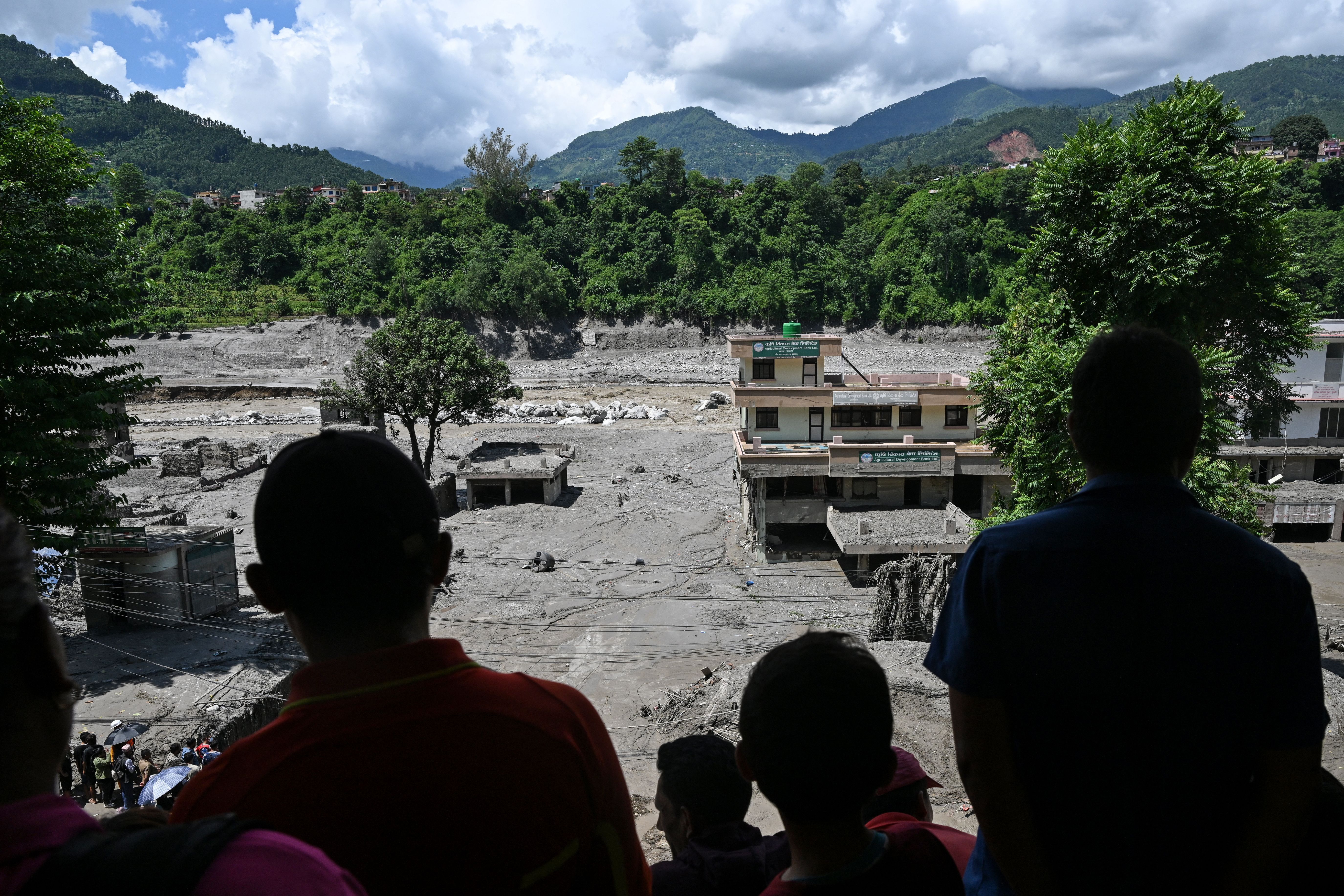 Pessoas em um telhado observam os danos causados ​​por enchentes repentinas em Trishuli, Nepal, na quinta-feira, 27 de agosto. • Arun Sankar/AFP/Getty Images via CNN Newsource