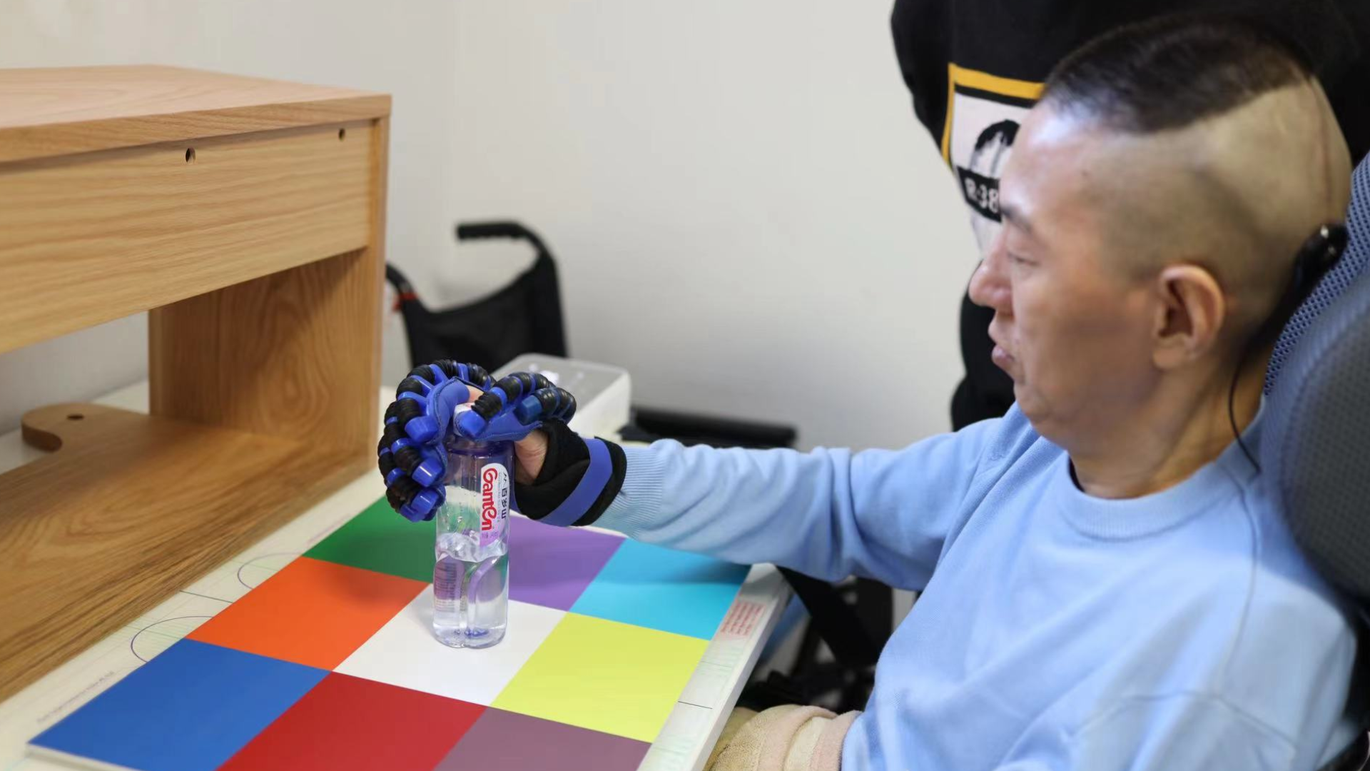 O paciente segura uma garrafa usando o sistema BCI sem fio NEO e uma prótese de mão. • Universidade de Tsinghua